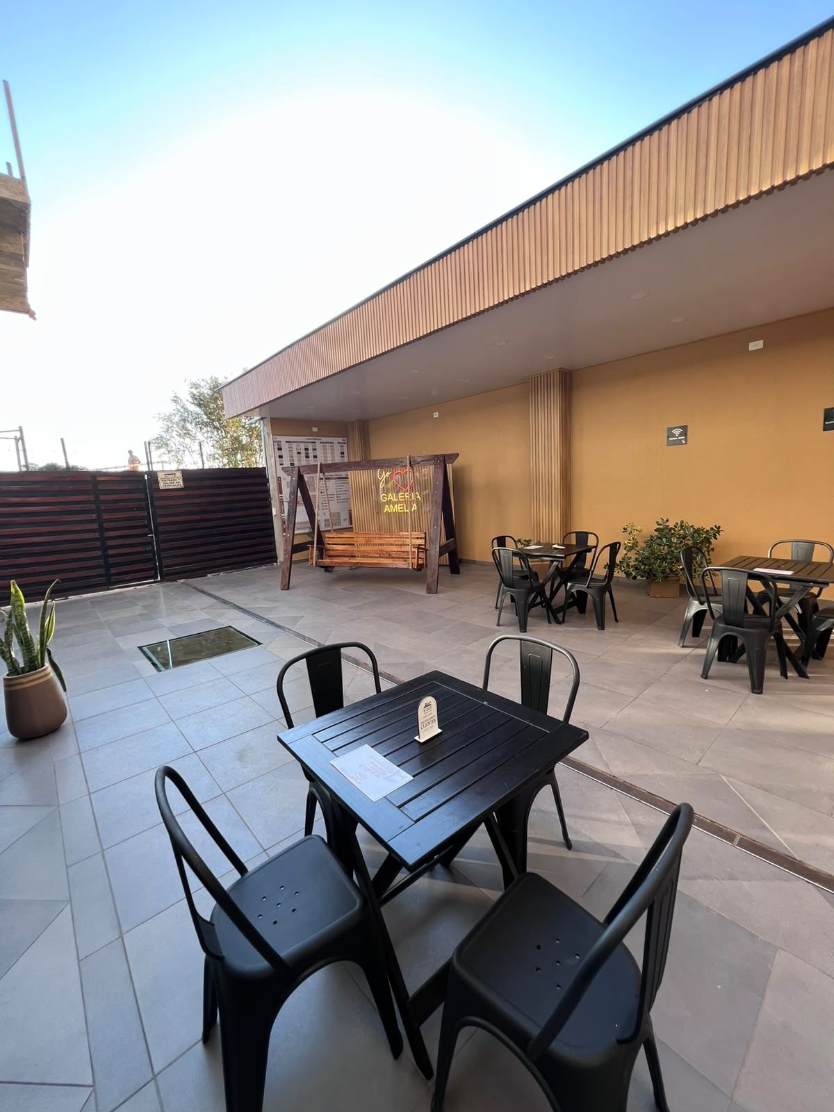 Patio exterior con mesas y hamaca de madera